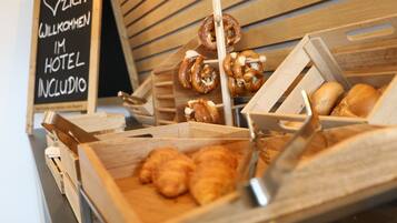 Una variedad de productos horneados, como pretzels, croissants y pan, presentados en cajas de madera.