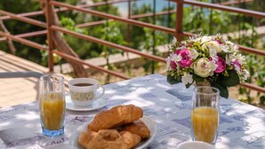 A table with croissants, coffee, and juice, overlooking a scenic view of the sea and mountains. - Rooms Sani (Brela)