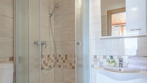 A modern bathroom with a glass-enclosed shower, a white sink, and a toilet. - Rooms Sani (Brela)
