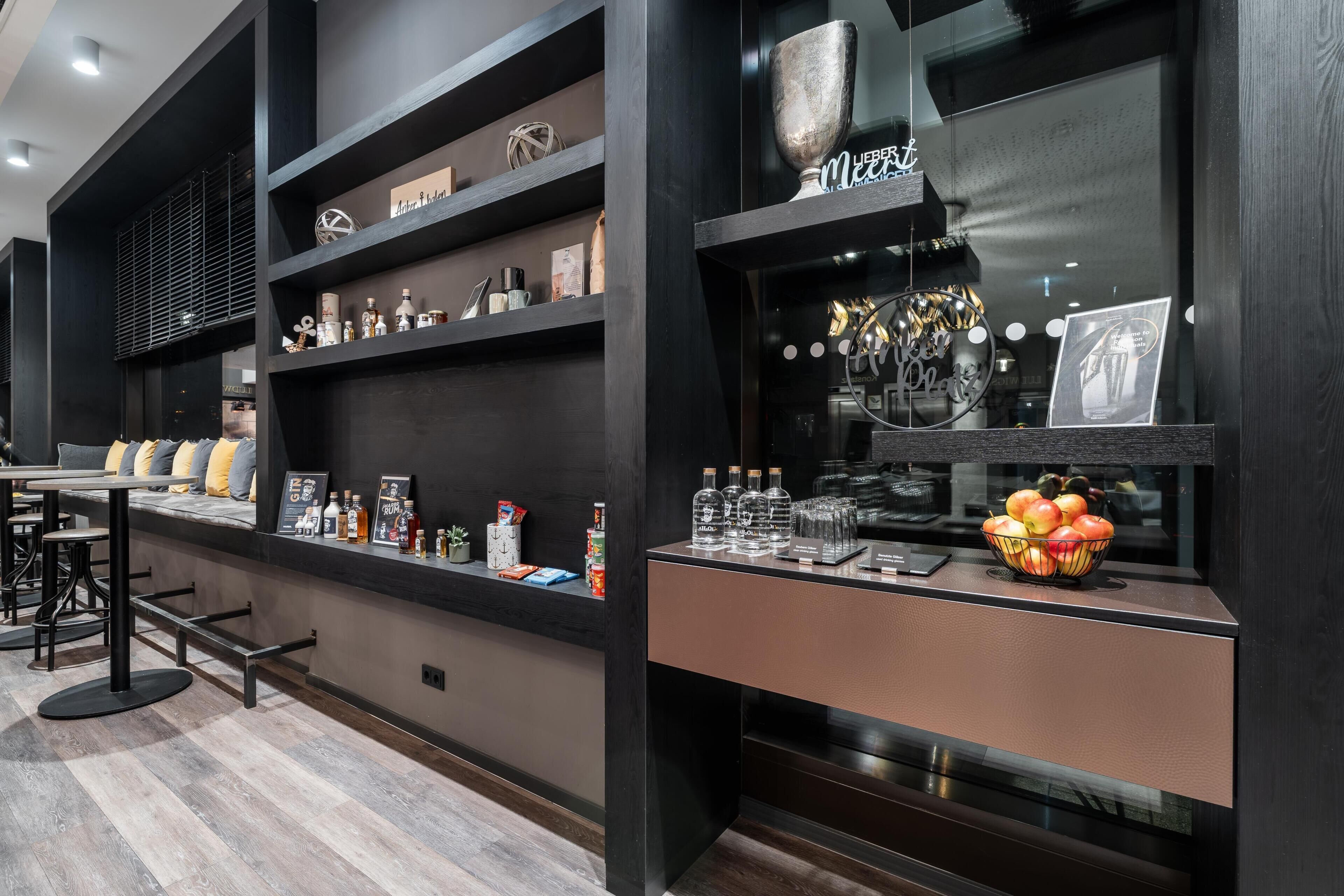 A modern bar area with shelves displaying bottles and a bowl of fruit.