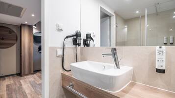 Een moderne badkamer met een witte wasbak, een spiegel en een haardroger.