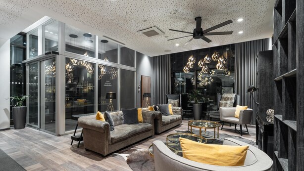Un salon moderne comprenant un canapé, des fauteuils, une table basse et un ventilateur de plafond.