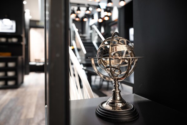 Un trophée est posé sur une table noire dans un intérieur moderne, avec un escalier en arrière-plan.