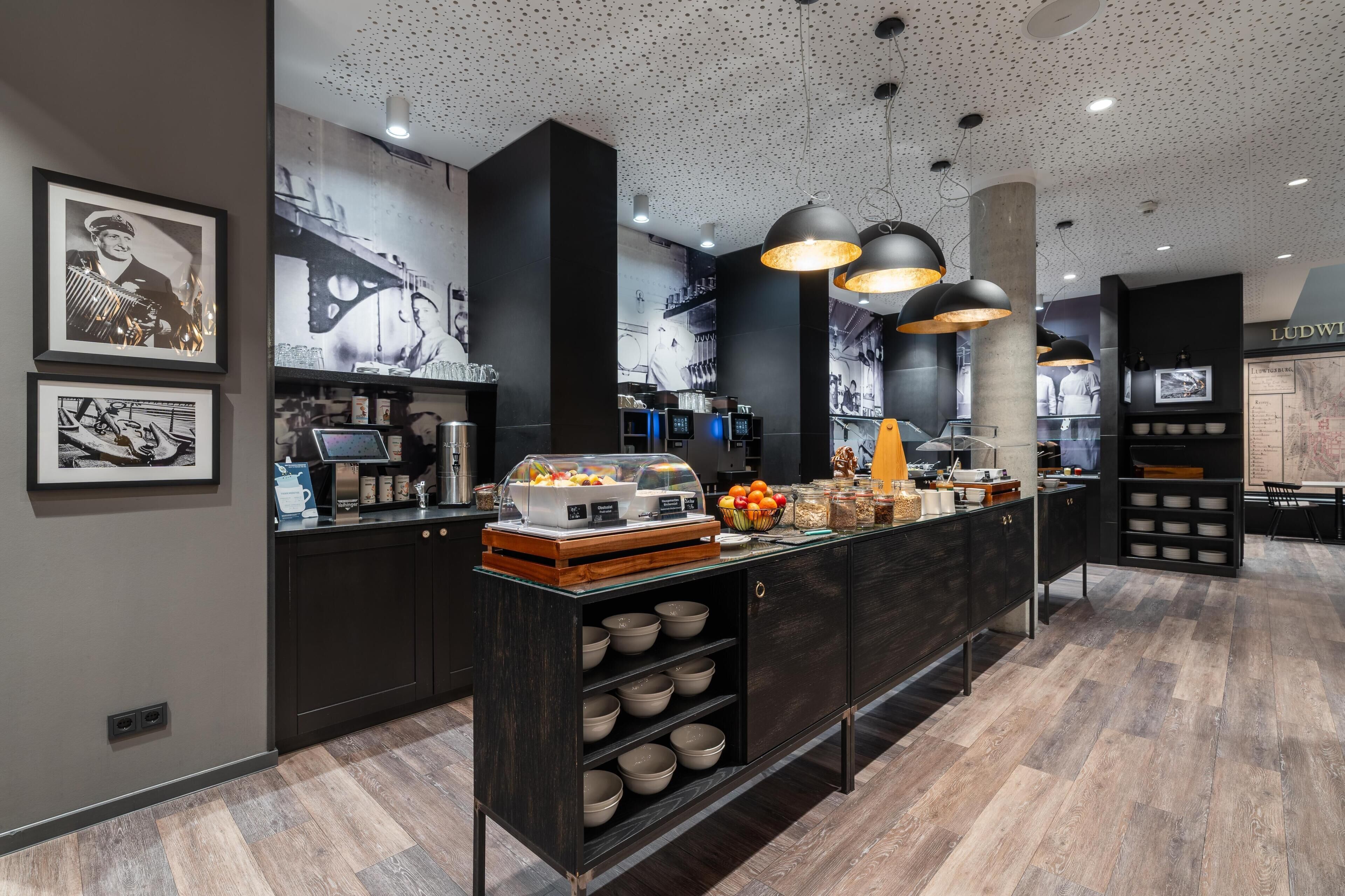 Een moderne keuken met een centraal eiland, zwarte kasten en een puntjes plafond.