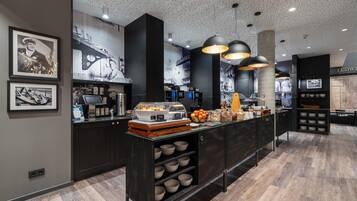 Een moderne keuken met een centraal eiland, zwarte kasten en een puntjes plafond.