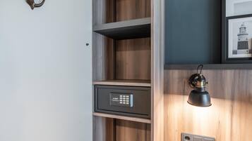 Un mueble de madera con caja fuerte integrada, una lámpara de pared y un cuadro enmarco.