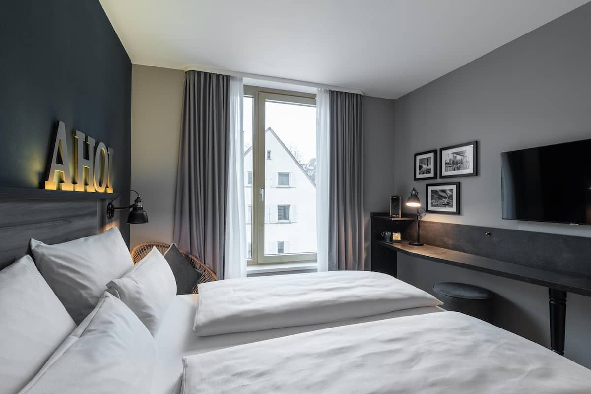 Een hotelkamer met een bed, een bureau, een televisie en een raam met gordijnen.
