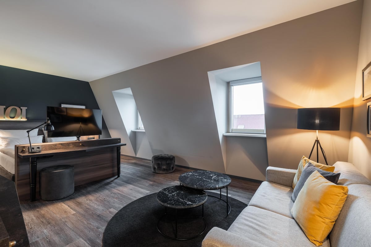 Een moderne loftkamer met een bed, een bureau, een bank en een eettafel.