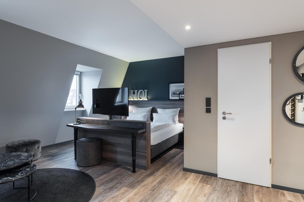 Een moderne hotelkamer met een bed, een bureau, een televisie en een ronde spiegel.