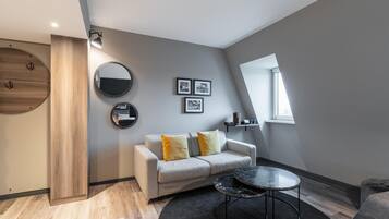 A modern living room with a sofa, round mirrors, framed pictures, a round coffee table, and a window.