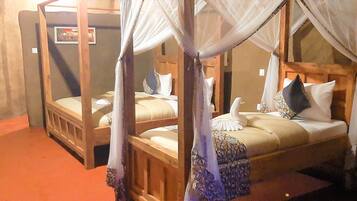 A room with two wooden beds, each with a canopy.