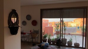 A balcony with potted plants, a table with chairs, and a view of buildings.