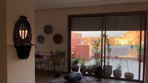 Ein Balkon mit Blumentöpfen, einem Tisch mit Stühlen und Blick auf Gebäude.