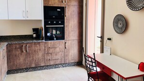 Eine Küche mit Holzschränken, einem eingebauten Backofen und einem Essbereich mit Tisch und Stühlen.