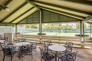 Enjoy a game of tennis with a clear view from the seating area, surrounded by a fence and a bench.