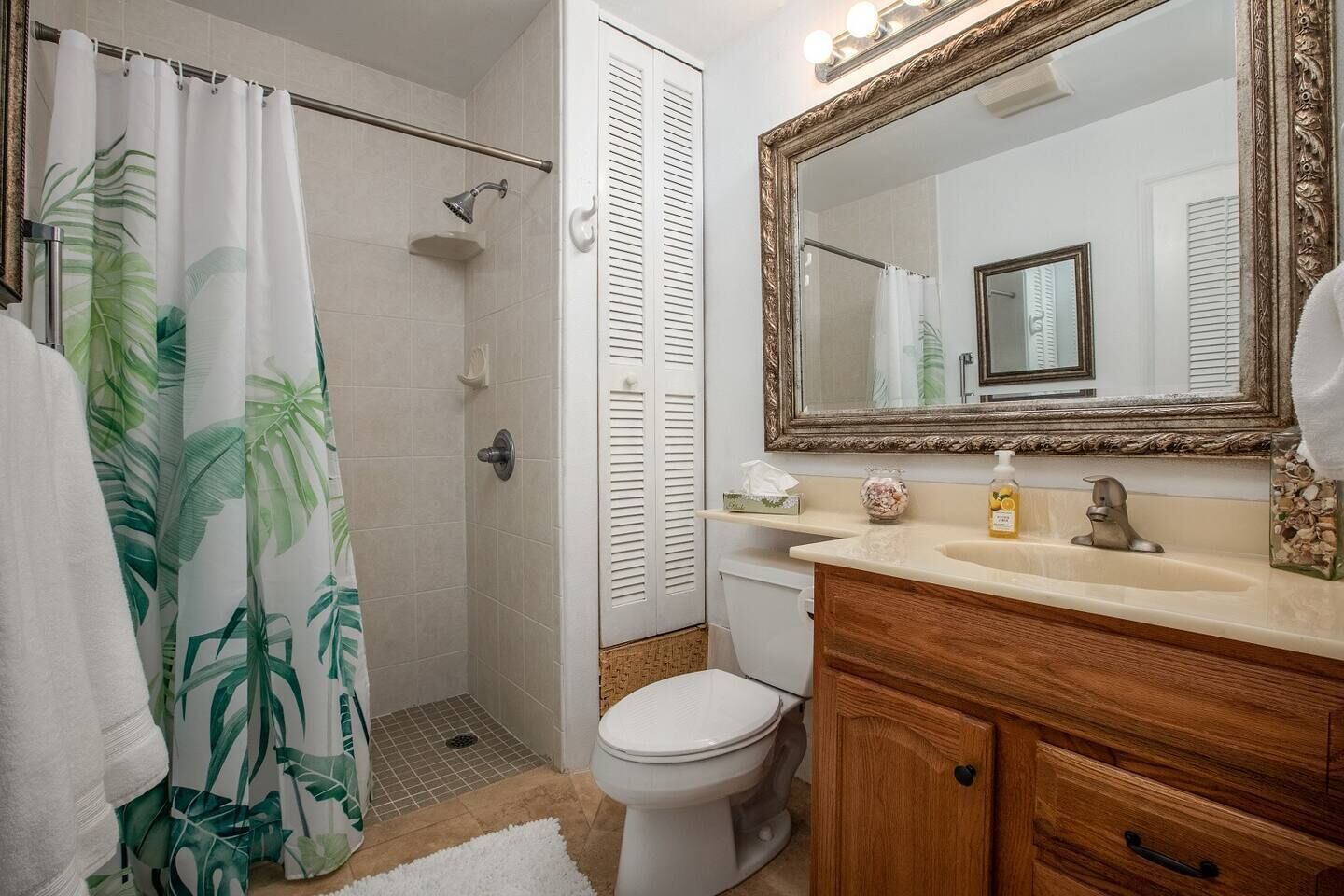Une salle de bain équipée d’une douche, de toilettes, d’un meuble-lavabo avec un miroir et d’un évier.