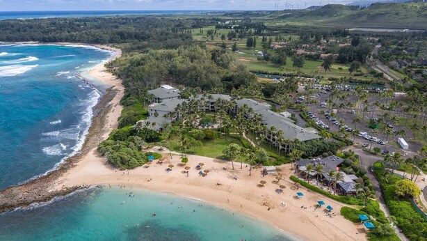 An aerial view of a coastal resort with a beach, clear turquoise waters, and a golf course in the background. - Honu Kai@Turtle Bay- Pool, AC, Golf, Beach (Kahuku)