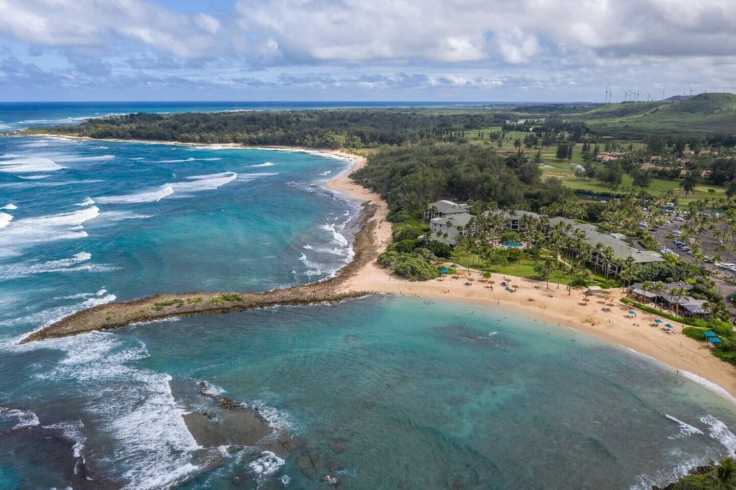 Un complejo turístico en la costa con playa, vistas al océano y un campo de golf.