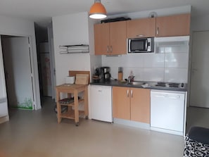 A compact kitchen with wooden cabinets, a microwave, a coffee maker, and a sink. - Ski-in/Ski-out: Cozy Apartment for 6 with Mountain Views, Parking & Modern Amenities (Arette)