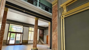 A spacious lobby with marble columns, a patterned floor, and a staircase leading to an upper level.