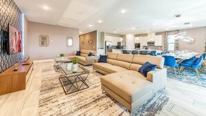 A modern living room with a sofa, coffee table, and a dining area with blue chairs.