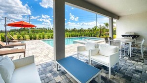 A poolside area with a hot tub, lounge chairs, and a barbecue grill.