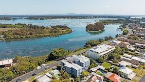 Et boligområde med moderne bygninger, en lystbådehavn med både og en flod med klart vand.