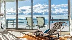 A balcony with two lounge chairs and a view of the sea.