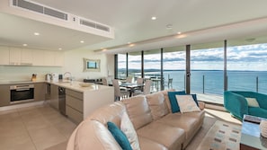 Enjoy a spacious living area with a leather sofa and dining table for four, overlooking a scenic sea view.