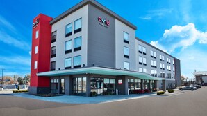 A modern hotel with a red and grey facade, large windows, and a covered entrance area. - avid hotel Detroit Warren by IHG (Warren)