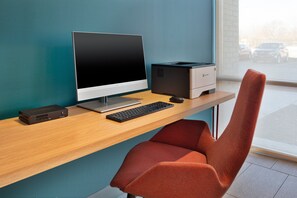 A modern office desk with a desktop computer, a printer, and a red office chair. - avid hotel Detroit Warren by IHG (Warren)