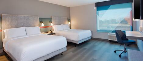 A hotel room with two beds, a desk, and a chair.