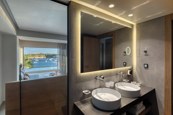 Un baño moderno con dos lavamanos, un espejo grande y vista al mar.