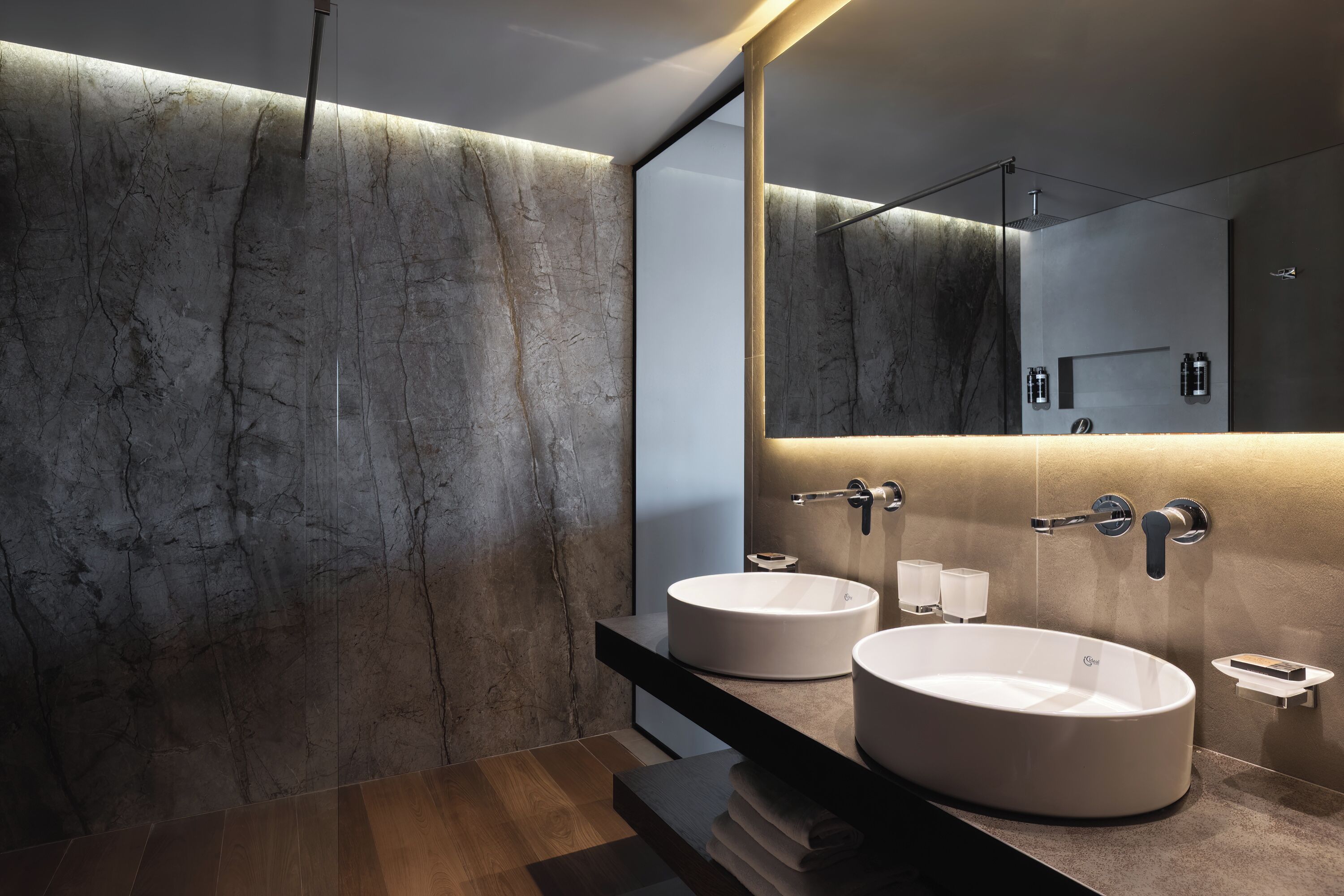 A modern bathroom with two round sinks, a large mirror, and a sleek design.