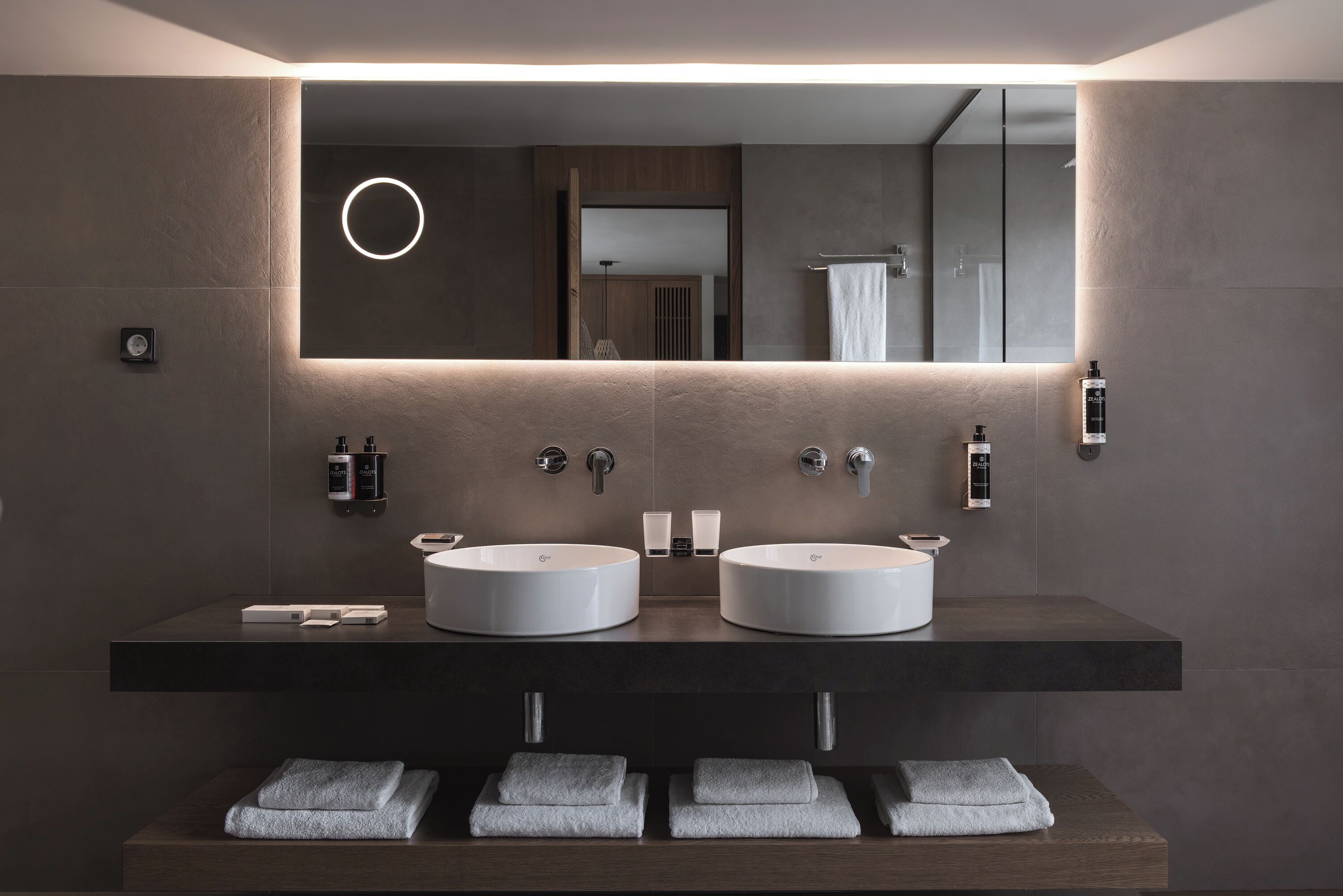 A modern bathroom with two sinks, a large mirror, and a towel rack.