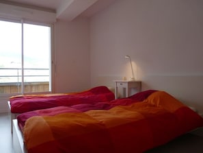 A bedroom with two beds, a nightstand, and a window. - Cozy 4-person apartment with ski-in access, dishwasher, washing machine, ski locker, free parking (Arette)
