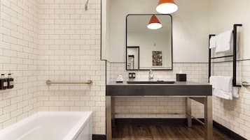 A modern bathroom with white subway tiles, a black sink, and a wooden floor.