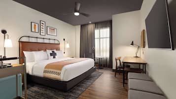 A modern hotel room with a large bed, a desk, and a chair.