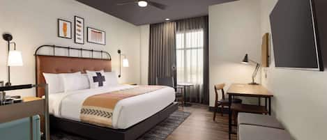 A modern hotel room with a large bed, a desk, and a chair.