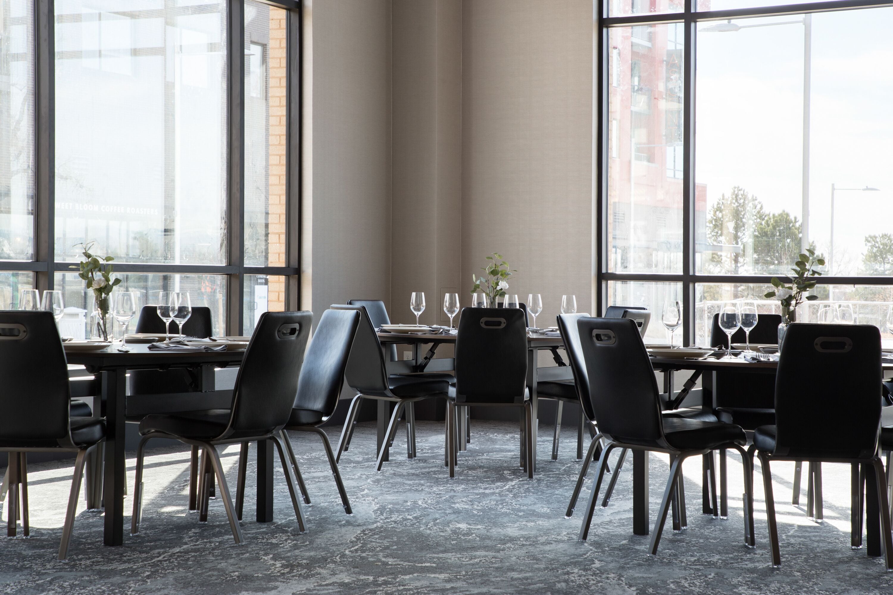 Un comedor moderno con una mesa larga dispuesta para una comida, ventanas amplias y vistas de la ciudad.