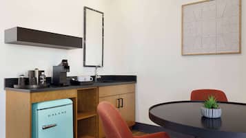 Quarto moderno com cozinha, mesa de jantar com planta e uma cadeira vermelha.