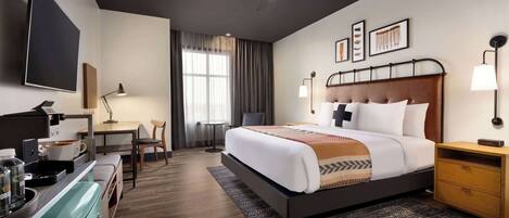 Une chambre d’hôtel avec un lit, un bureau et une kitchenette.