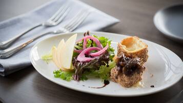 A plate with a salad and a breaded item, accompanied by a fork and knife on a napkin.