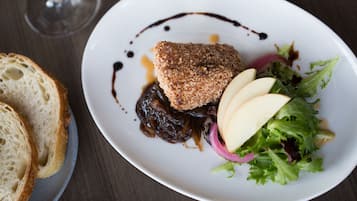 A plate with a breaded item, sliced apples, and a salad on a white plate.