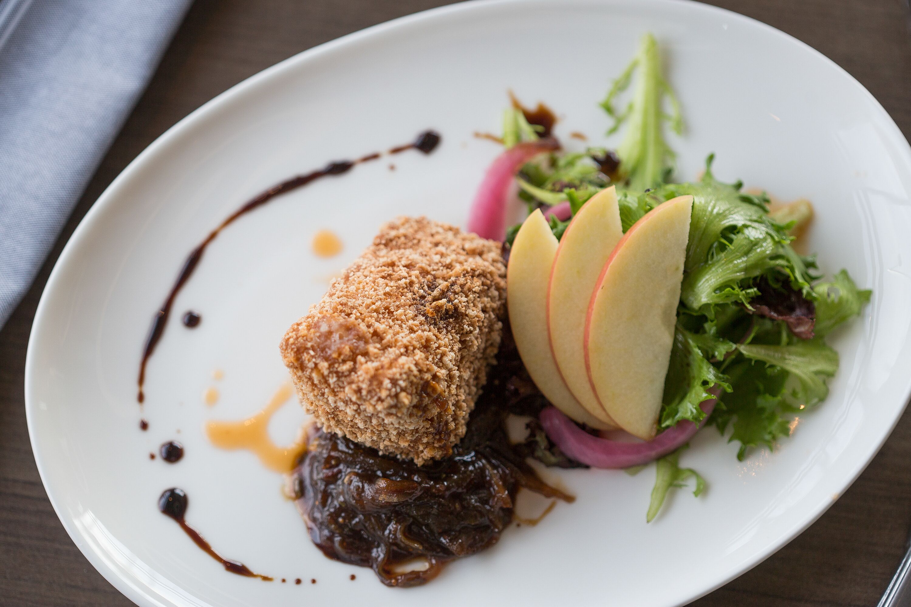 A plate with a dessert, apple slices, and a salad.