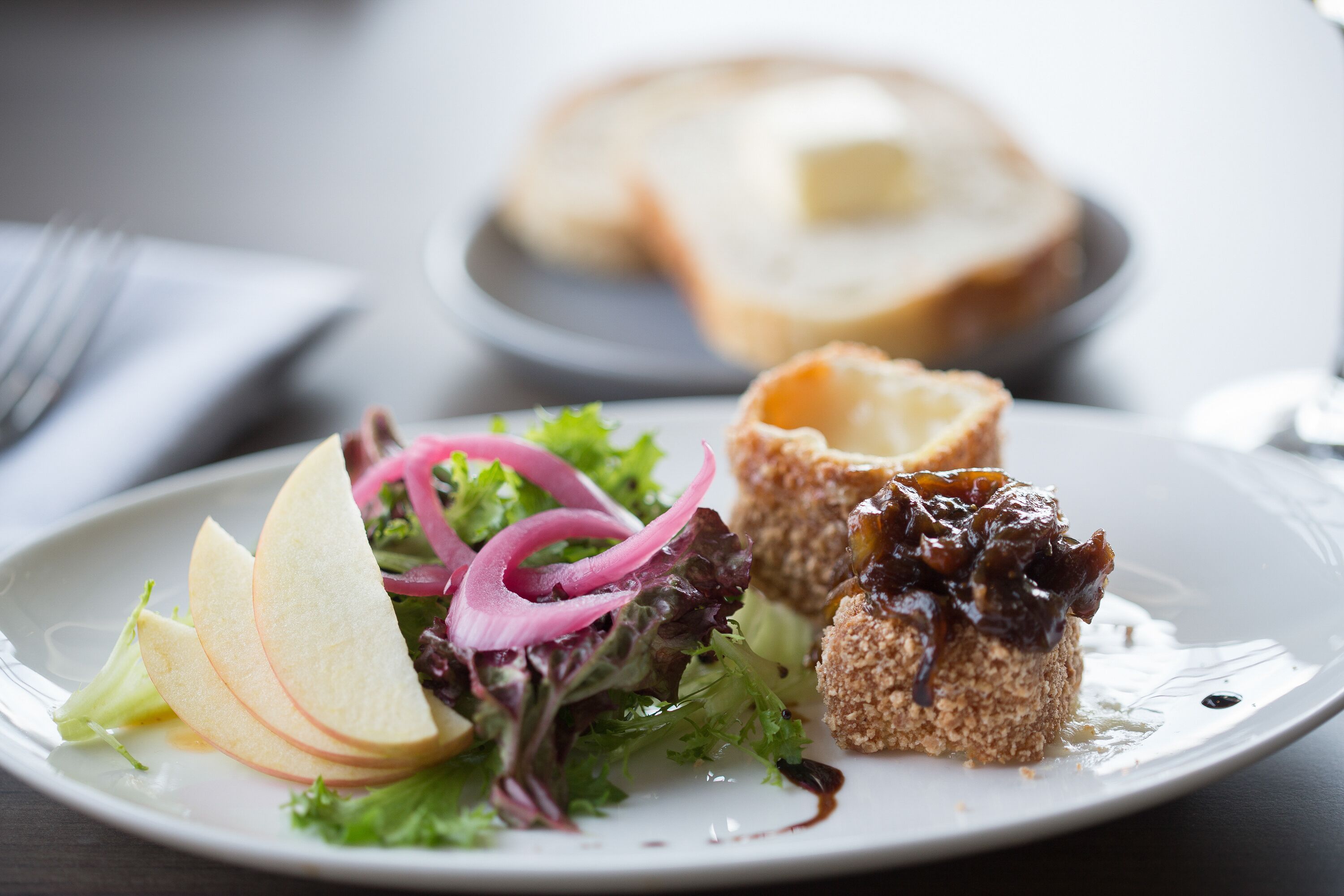Een bord met salade, brood en toetje.