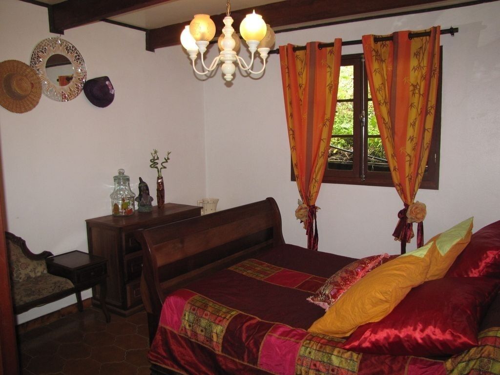 A bedroom with a wooden bed, a nightstand, a dresser, and a chandelier.