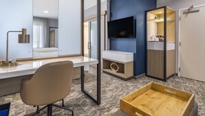 Ett modernt hotellrum med ett stort skrivbord, en stol, en tv som är monterad på väggen och ett litet bord i trä.