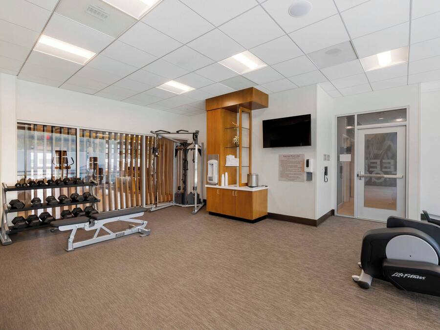 Un gimnasio con equipamiento de ejercicio, una recepción y un televisor en la pared.