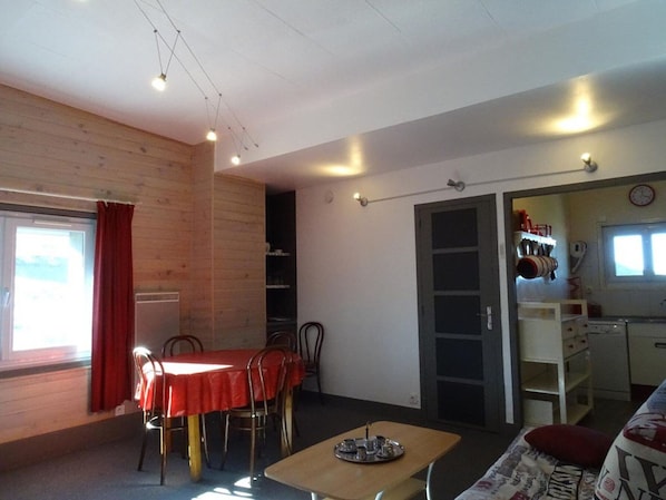 A compact living space with a dining area, kitchenette, and a view of the outdoors.